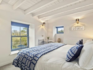 White bedroom with double bed and blue patterned throw