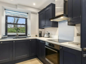 Modern kitchen with dark cabinets, white worktops, built-in oven and hob