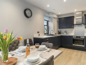 Modern kitchen with dark cabinets, built-in oven and dining table set for eight