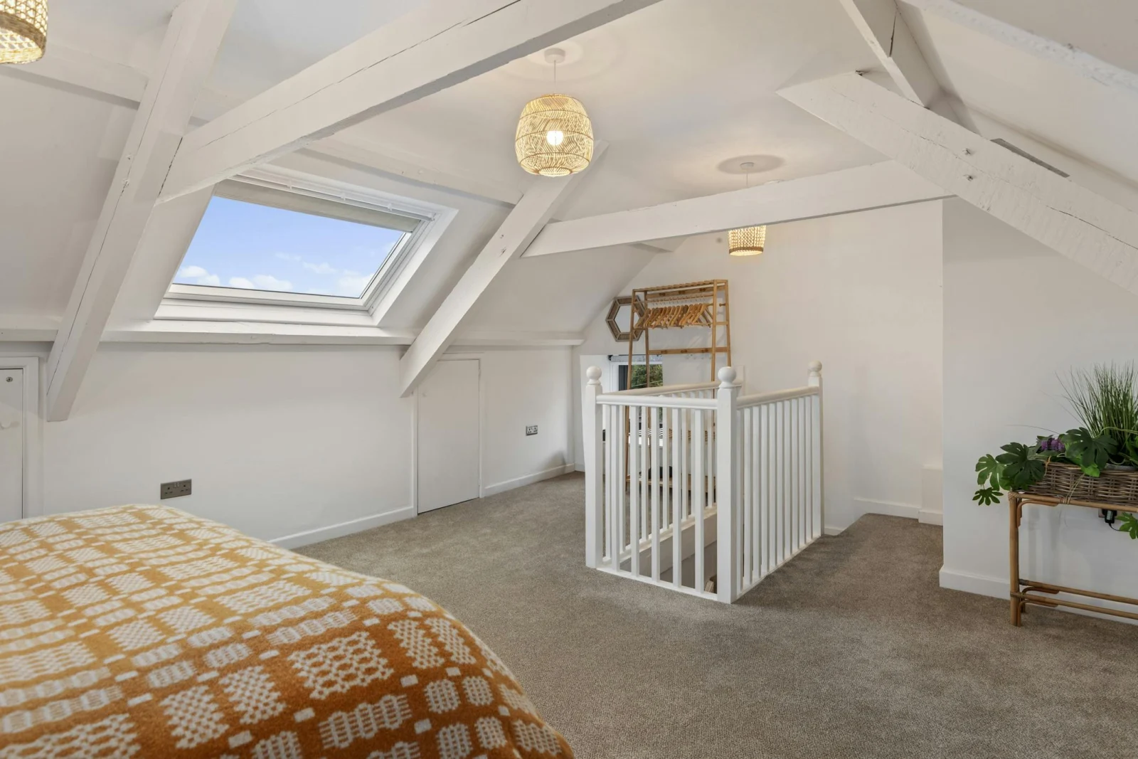 Loft bedroom with white beams, skylight, carpeted floor and stair railing