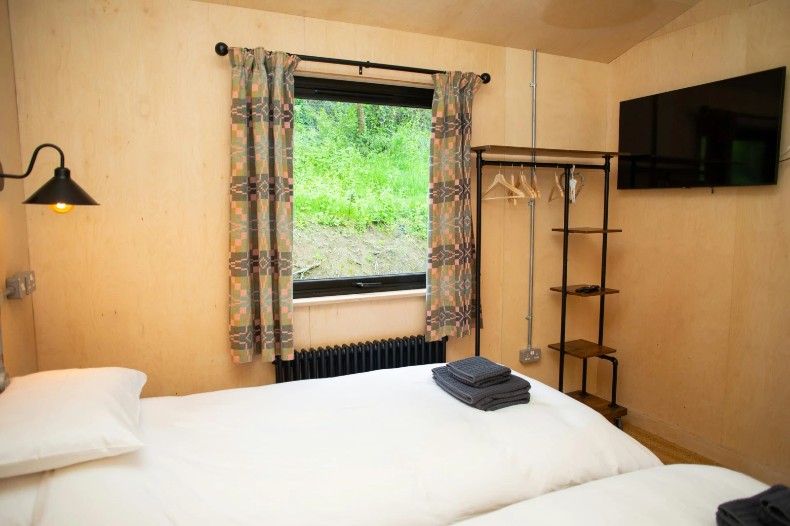 Twin bedroom with clothes hanging rail and wall mounted TV