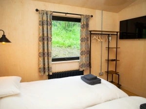 Twin bedroom with clothes hanging rail and wall mounted TV