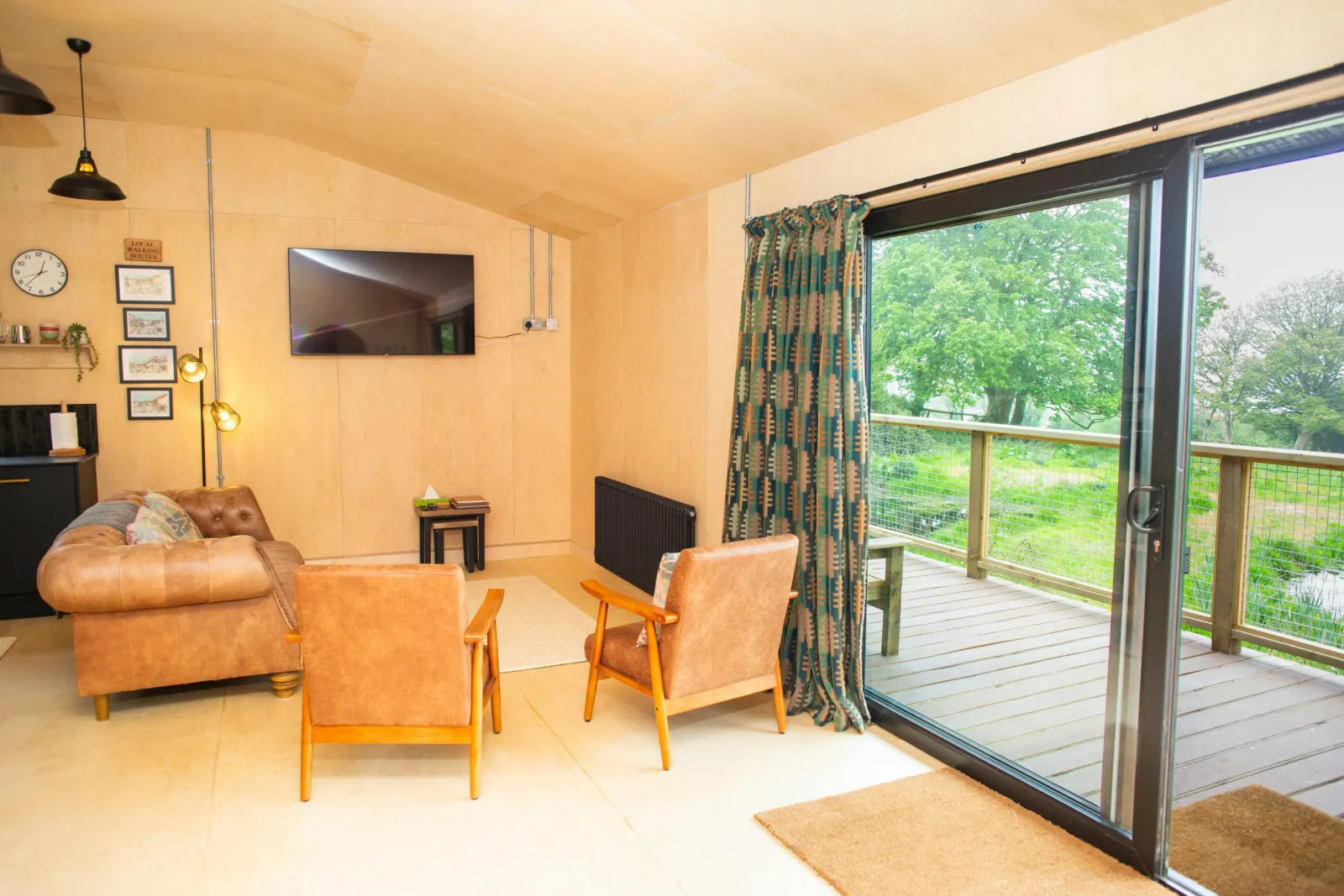 Sitting area with leather sofas and armchairs and patio doors leading to the veranda