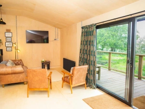 Sitting area with leather sofas and armchairs and patio doors leading to the veranda