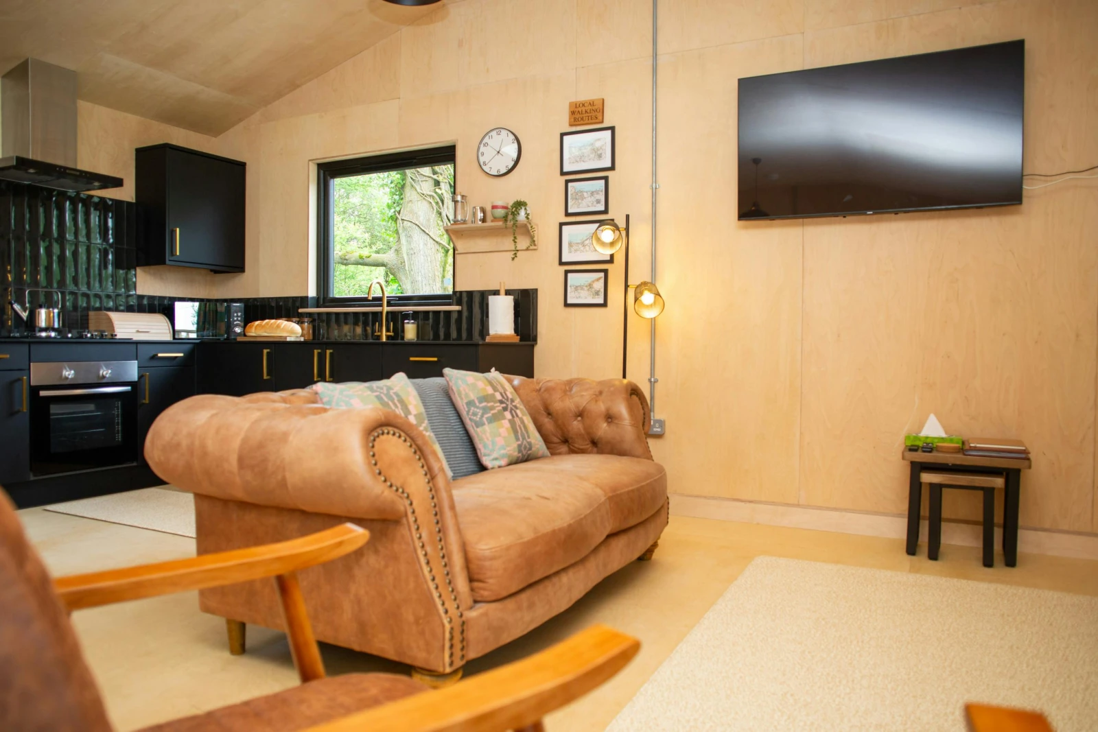 Sitting area with brown Chesterfield style sofa and wall  mounted TV