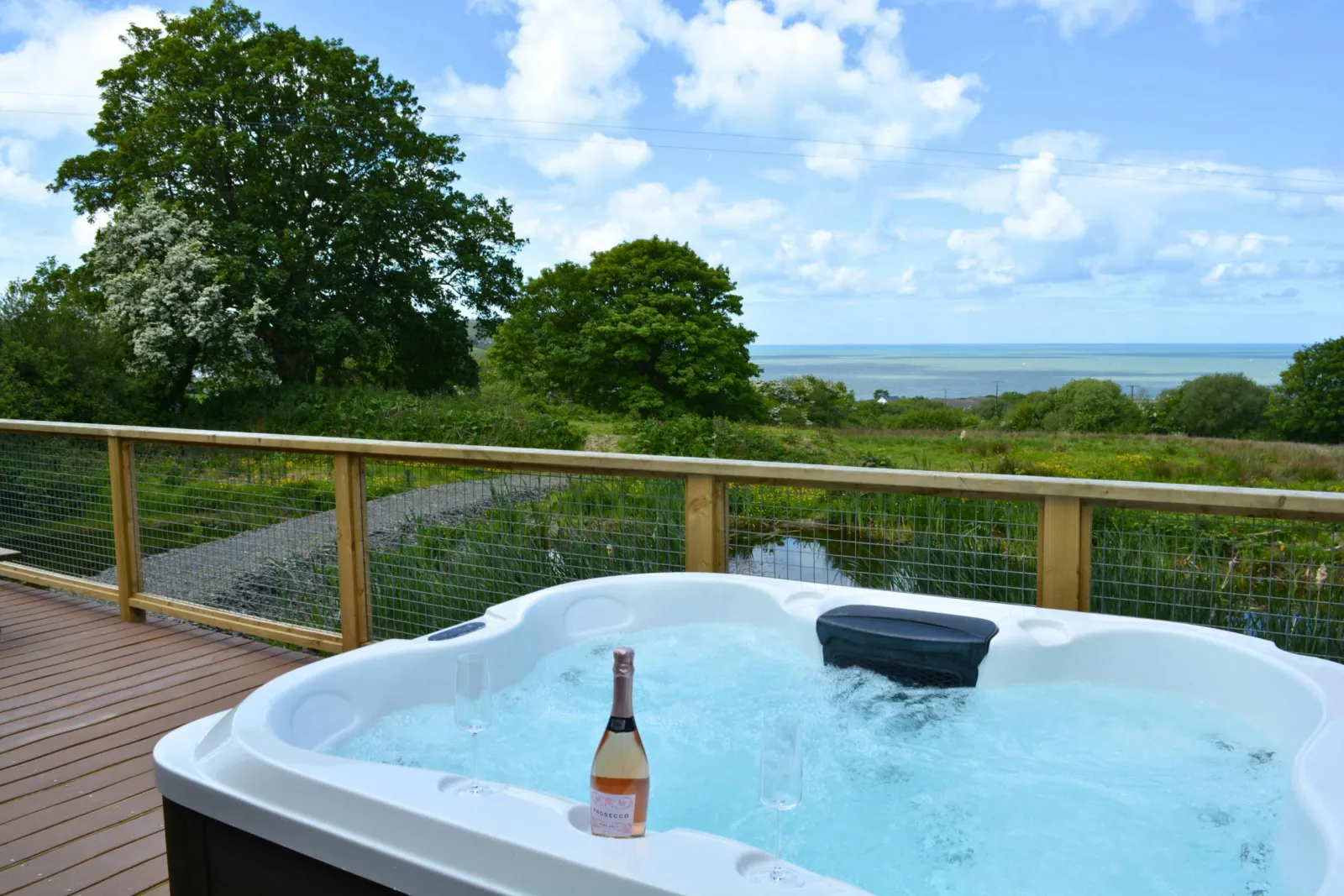 Outdoor hot tub on wooden deck with sea view and trees