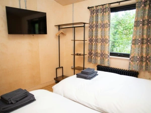 Twin bedroom with clothes hanging rail and wall mounted TV
