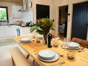 Dining area with table bench and two chairs. Laid for dinner with a vase of flowers