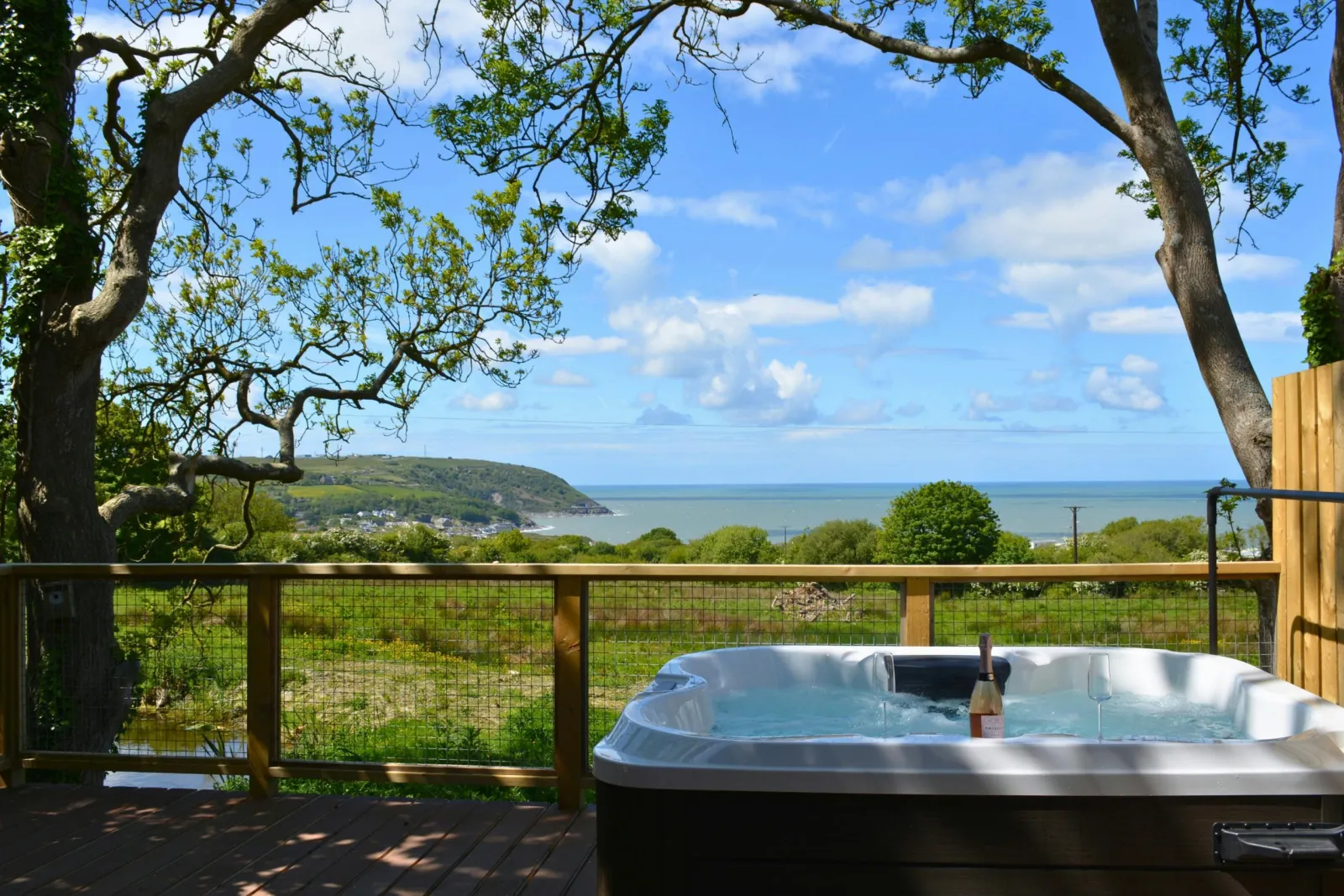 Hot tub on a wooden deck overlooking the sea and distant hills