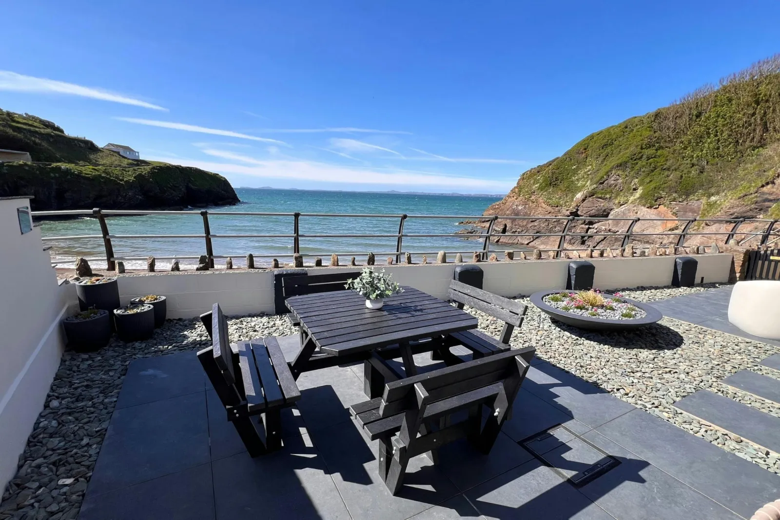 Seaside patio with picnic table and benches overlooking the ocean