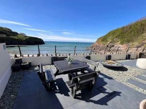 Seaside patio with picnic table and benches overlooking the ocean