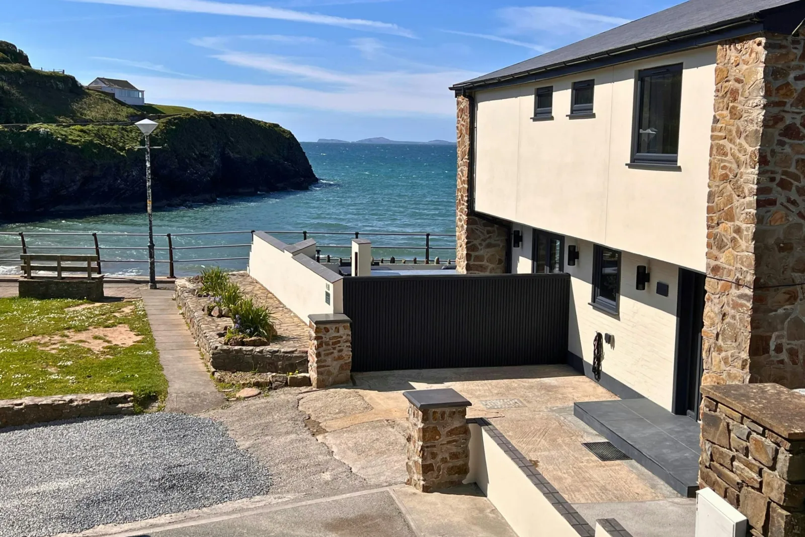 Seafront house exterior with terrace walls and path leading towards the water