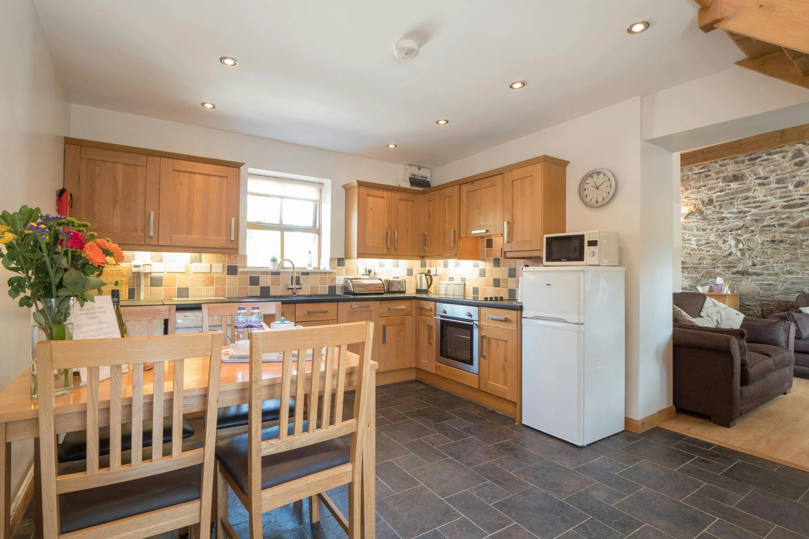 Fitted kitchen with cooker, fridge/freezer, microwave, kettle, toaster; dining table with four chairs