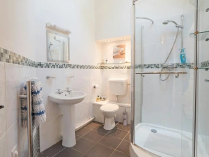 Large shower enclosure, WC, hand basin with mirror above, heated towel rail