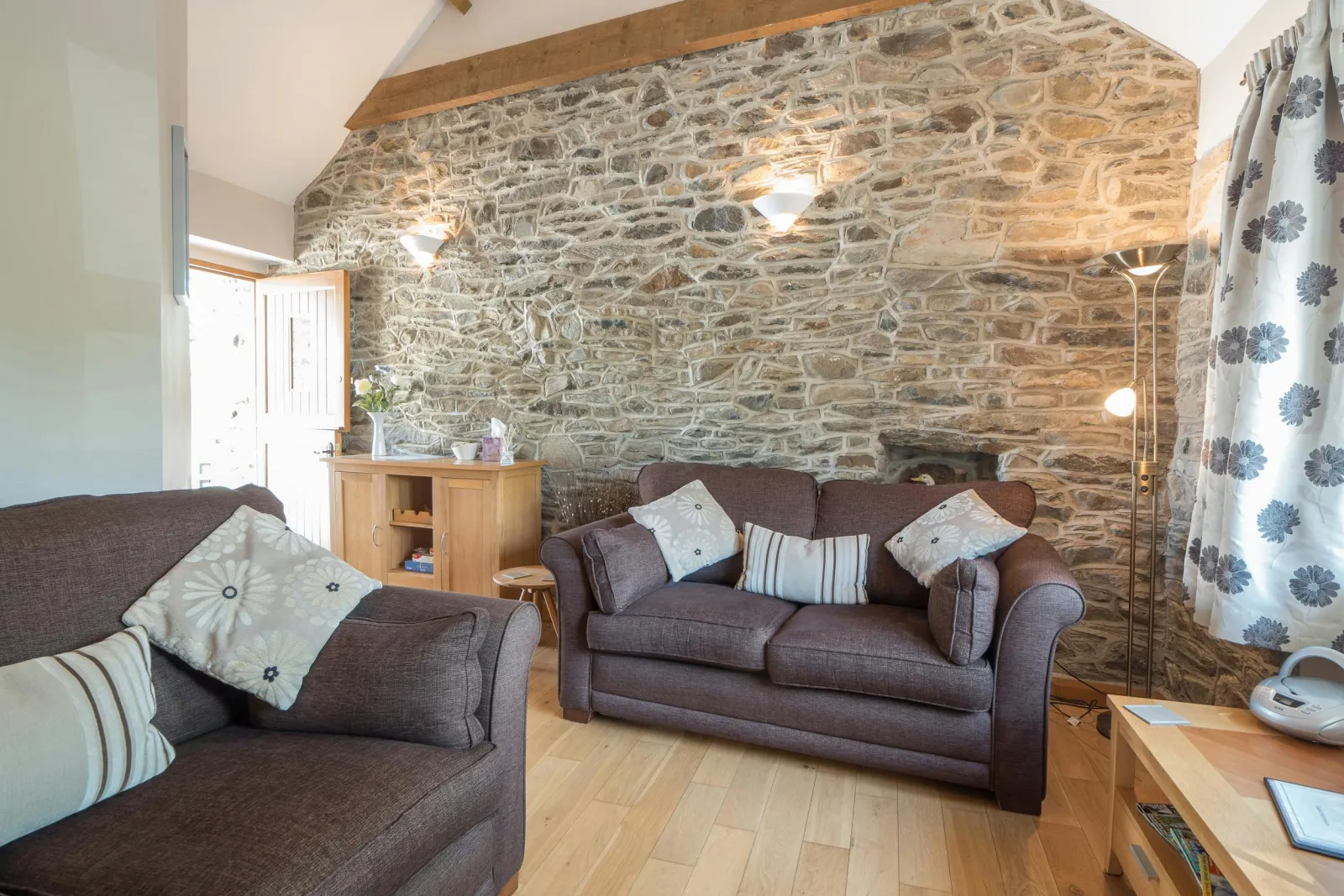 Living room in Briallen, exposed stone wall, 2 sofas, lamps, wooden furniture