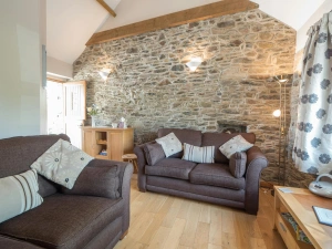 Living room in Briallen, exposed stone wall, 2 sofas, lamps, wooden furniture