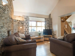 Sofas facing window, coffee table and unit with TV, standard lamp, wooden staircase to upstaris