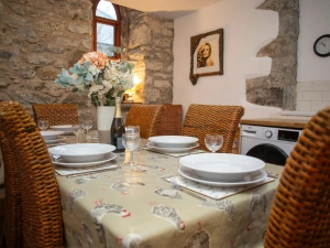 Rustic dining room with stone walls, set table and vase of flowers under a small window