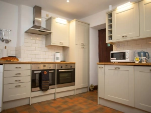 Cream kitchen with white tiled splashback, double oven and extractor hood