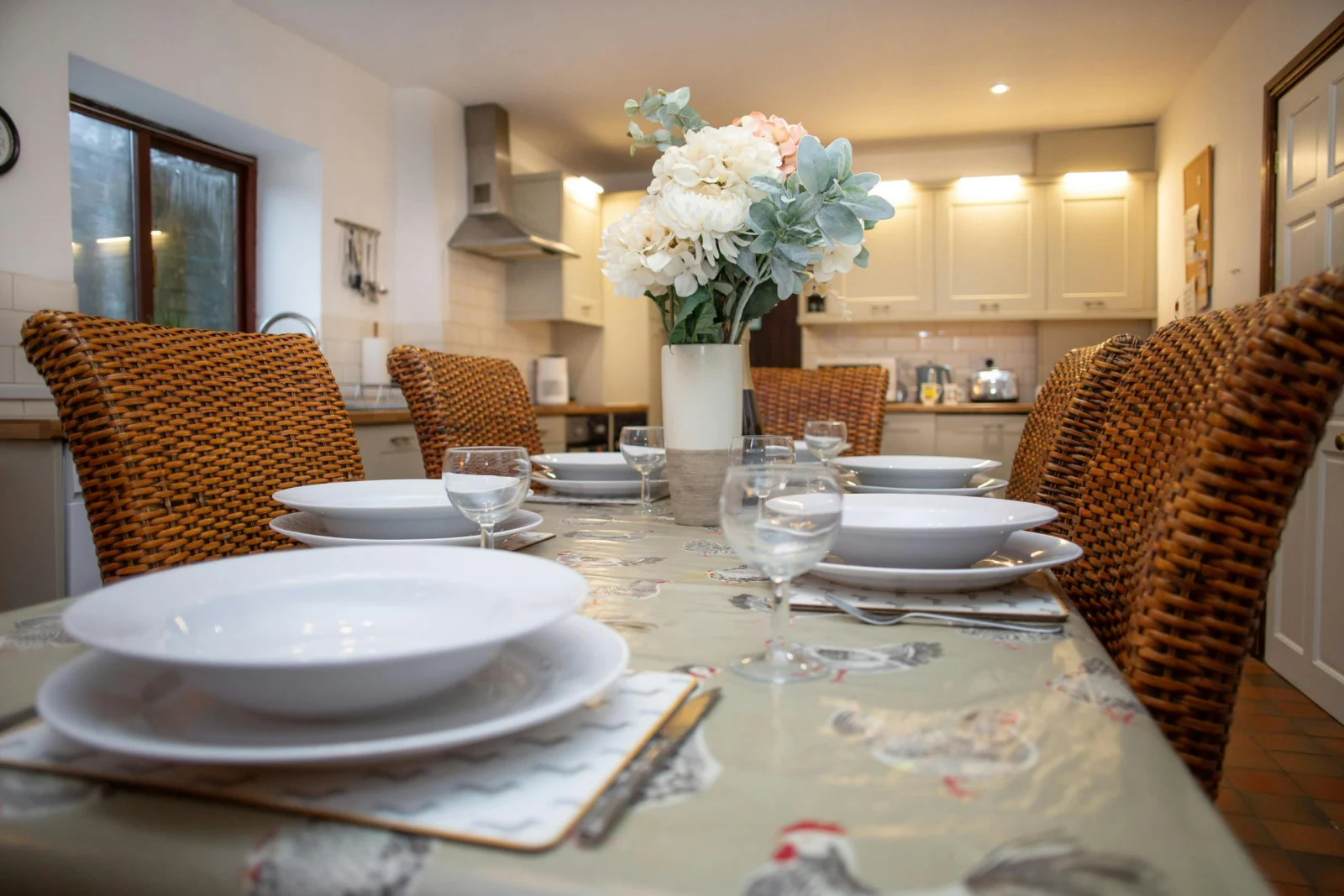 Table laid for a meal with stacked plates and glasses, flowers in a vase