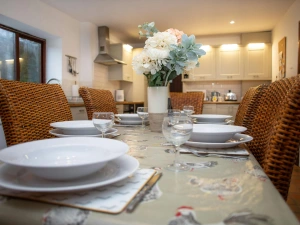 Table laid for a meal with stacked plates and glasses, flowers in a vase