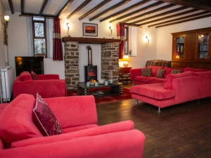 Red sofas around a stone fireplace in a beamed ceiling lounge