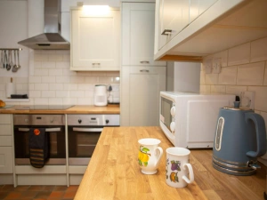 Modern kitchen with wooden worktop, microwave, kettle and two mugs