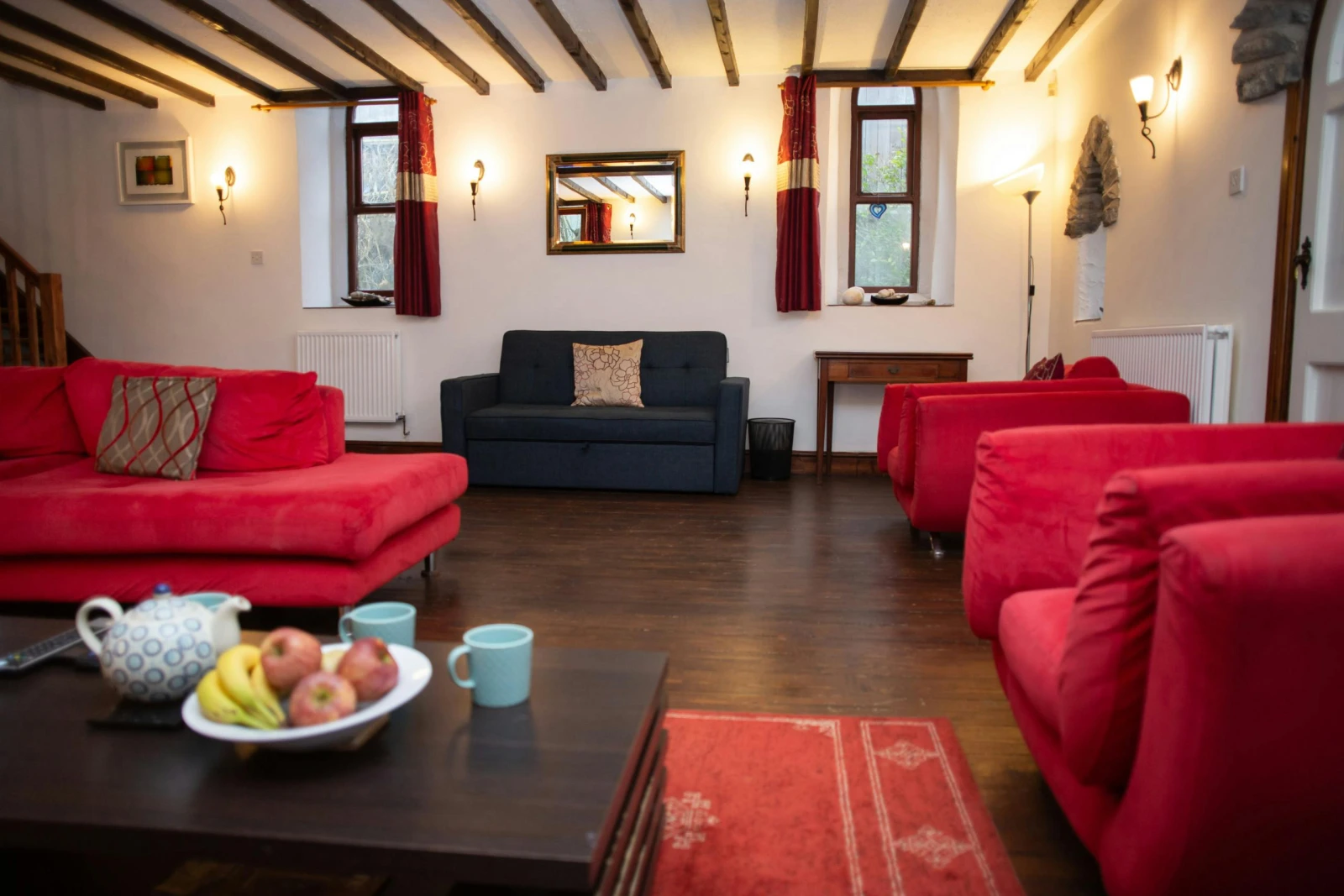 Spacious lounge with red sofas, blue sofa, rug and wooden floor