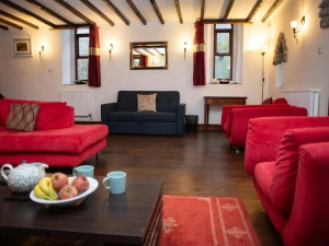 Spacious lounge with red sofas, blue sofa, rug and wooden floor