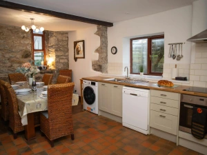 Rustic kitchen with stone walls, dining table and wicker chairs