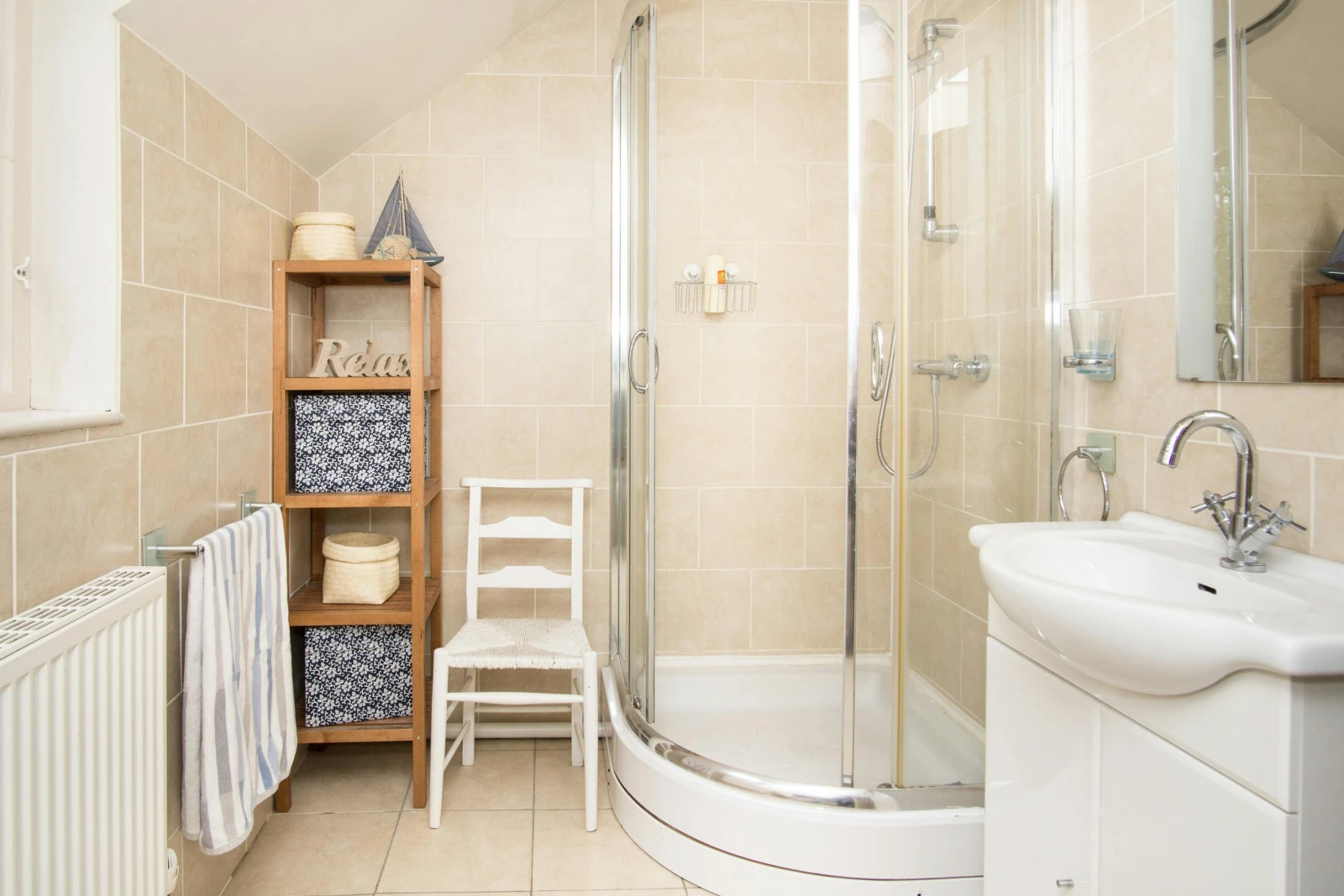 One of 3 bathrooms with shower cubicle, chair and hand basin with mirror above