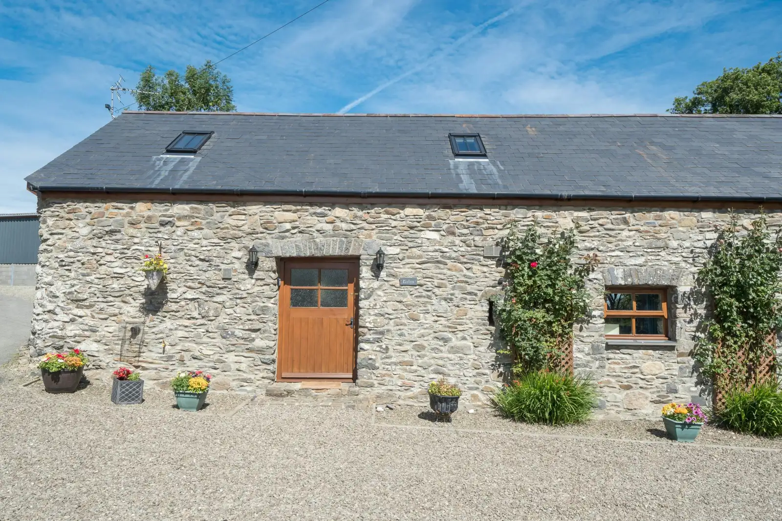 Eirlys, a stone cottage with flower pots in front